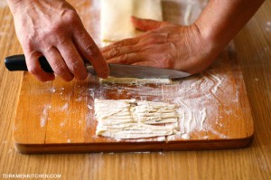 Place one hand on the folded dough as a guide and using a sharp knife, cut into thin noodles.